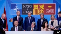 From left to right: NATO Secretary General, Turkish President, Finland's President, Sweden's Prime Minister, Turkish Foreign Minister, Finnish Foreign Minister, and Sweden's Foreign Minister sign a memorandum in Madrid, Spain, on June 28, 2022.