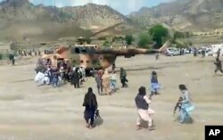 In this image taken from video from Bakhtar State News Agency, Taliban fighters secure a government helicopter to evacuate injured people in Gayan district, Paktika province, Afghanistan, Wednesday, June 22, 2022. (Bakhtar State News Agency via AP)