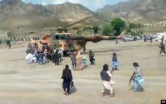 In this image taken from video from Bakhtar State News Agency, Taliban fighters secure a government helicopter to evacuate injured people in Gayan district, Paktika province, Afghanistan, Wednesday, June 22, 2022. (Bakhtar State News Agency via AP)