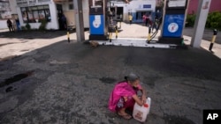 FILE - A Sri Lankan woman waits in a deserted gas station, hoping to buy kerosene oil for cooking in Colombo, Sri Lanka, May 26, 2022. Sri Lanka has run out of fuel, according to a report in Monday's Daily Mirror.