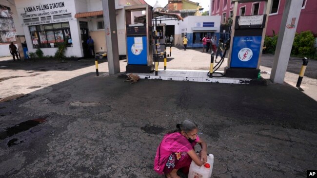 FILE - A Sri Lankan woman waits in a deserted gas station, hoping to buy kerosene oil for cooking in Colombo, Sri Lanka, May 26, 2022.