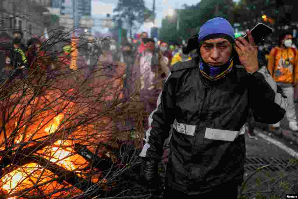 Un manifestante se encuentra junto a un bloqueo de carretera en llamas en Quito.