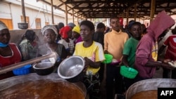 FILE - Refugees from the Democratic Republic of Congo (DRC) receive lunch at the Nyakabande Transit Center in Kisoro, Uganda, June 7, 2022, following deadly fights between M23 rebels and DRC troops.