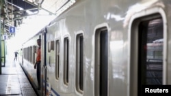 Seorang petugas kereta api tampak menunggu penumpang untuk menaiki kereta sebelum kereta berangkat dari Jakarta menuju Bandung dalam perjalanan yang dimulai dari Stasiun Gambir, Jakarta, pada 30 September 2015. (Foto: Reuters/Nyimas Laula)