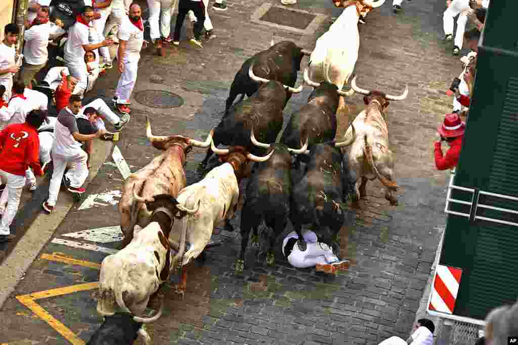 A runner falls as people run through the street with fighting bulls at the San Fermin Festival in Pamplona, northern Spain.