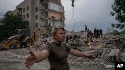 Seorang anngota pasukan Ukraina meminta awak media untuk mundur dari lokasi reruntuhan gedung yang hancur dihantam oleh rudal Rusia di Chasiv Yar, wilayah Donetsk pada 10 Juli 2022. (Foto: AP/Nariman El-Mofty) 