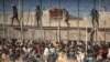 Polisi anti huru-hara memasang pengaman ketika para migran tiba di wilayah Spanyol setelah menyeberangi pagar yang memisahkan kantong Spanyol dan Maroko di Melilla, Spanyol, Jumat, 24 Juni 2022. (Foto: AP Photo/Javier Bernardo)