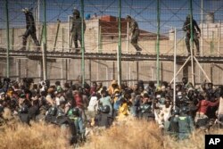 Agentes de la policía antidisturbios acordonan el área después de que los migrantes llegan a suelo español después de cruzar las vallas que separan el enclave español de Melilla de Marruecos en Melilla, España, el 24 de junio de 2022.