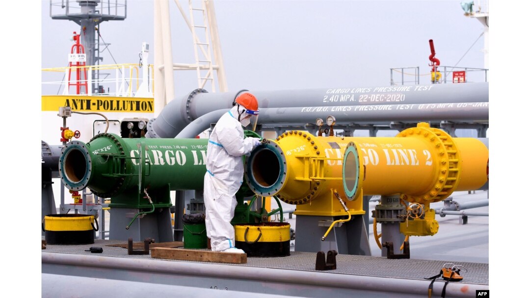 Seorang petugas inspeksi memeriksa sebuah kapal tanker yang membawa minyak mentah impor di pelabuhan Qingdao di provinsi Shandong timur China, 9 Mei 2022. (Foto: AFP)