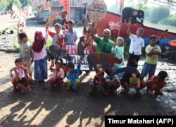 Pensiunan guru Samsudin (tengah R) mengajar anak-anak tentang konservasi hewan dengan boneka kardus di desa Cemara Kulon, Indramayu. (Foto: AFP/Timur Matahari)