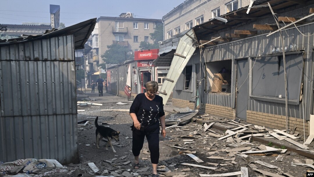 Una mujer pasa por tiendas destruidas en un mercado local después de un ataque con cohetes en la ciudad ucraniana de Sloviansk, el 3 de julio de 2022, en medio de la invasión rusa de Ucrania.
