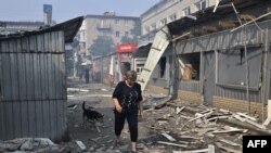 Una mujer pasa por tiendas destruidas en un mercado local después de un ataque con cohetes en la ciudad ucraniana de Sloviansk, el 3 de julio de 2022, en medio de la invasión rusa de Ucrania.