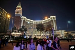 FILE - People walk in front of the Venetian Macao casino resorts in Macao, Nov. 23, 2014. The Asian gambling center of Macao will close all its casinos for a week starting July 11, 2022.