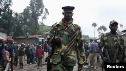 FILE - M23 rebel fighters walk through the city of Karuba, 62 km west of Goma, capital of North Kivu province in the eastern Democratic Republic of the Congo on November 28, 2012.  The top UN official for the DRC said on June 29, 2022, that the insurgent rebel group is posing a growing threat to civilians.