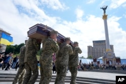 Soldiers carry the coffin of activist and soldier Roman Ratushnyi for a memorial service at Maidan square in Kyiv, Ukraine, June 18, 2022. Ratushnyi died in a battle near Izyum, where Russian and Ukrainian troops are fighting for control the area.