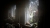 Rescue workers look thougt the window of a destroyed house after a Russian attack in a residential neighborhood in downtown Kharkiv, Ukraine, July 11, 2022.