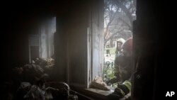 Rescue workers look thougt the window of a destroyed house after a Russian attack in a residential neighborhood in downtown Kharkiv, Ukraine, July 11, 2022.