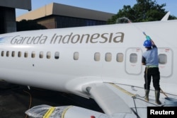Seorang pekerja membersihkan pesawat Garuda Indonesia yang diparkir di Garuda Maintenance Facility (GMF) AeroAsia, Bandara Internasional Soekarno-Hatta, Cengkareng, 21 Januari 2022. (REUTERS/Willy Kurniawan)