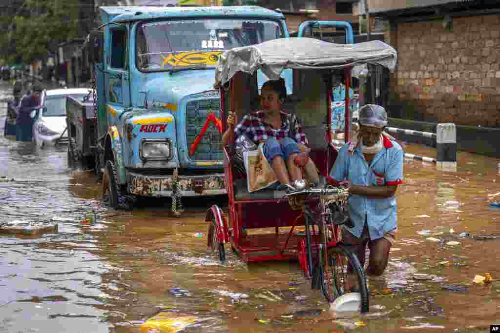 A rickshaw driver takes a passenger past a waterlogged street after continuous rainfall in Gauhati, India.