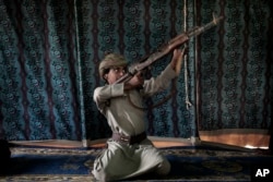 FILE - Kahlan, a 12-year-old former child soldier, demonstrates how to use a weapon, at a camp for displaced persons where he took shelter with his family, in Marib, Yemen, July 27, 2018. (AP Photo/Nariman El-Mofty, File)