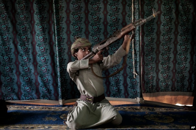 FILE - Kahlan, a 12-year-old former child soldier, demonstrates how to use a weapon, at a camp for displaced persons where he took shelter with his family, in Marib, Yemen, July 27, 2018. (AP Photo/Nariman El-Mofty, File)