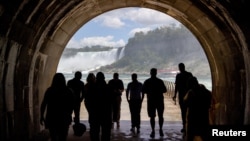FILE - People walk through a tunnel, a new tourist attraction, at at the Niagara Parks Power Station in Niagara Falls, Ontario, Canada, June 28, 2022. (REUTERS/Carlos Osorio)