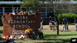 FILE - Investigators search for evidence outside Robb Elementary School in Uvalde, Texas, May 25, 2022, after an 18-year-old gunman killed 19 students and two teachers.