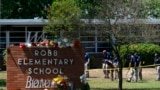 FILE - Investigators search for evidence outside Robb Elementary School in Uvalde, Texas, May 25, 2022, after an 18-year-old gunman killed 19 students and two teachers.