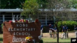 Para penyelidik tengah bekerja di luar sekolah dasar Robb di Uvalde, Texas, 25 Mei 2022, setelah terjadi penembakan yang menewaskan 19 murid dan 2 guru. (AP Photo/Jae C. Hong)
