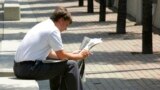 Un hombre lee un periódico durante su hora de almuerzo en Cincinnati el 6 de julio de 2005.