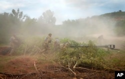 Tentara Ukraina menyembunyikan howitzer M777 yang dipasok AS dengan ranting pepohonan setelah mereka menembaki posisi Rusia di wilayah Donetsk timur Ukraina pada Sabtu, 18 Juni 2022. (Foto: AP)