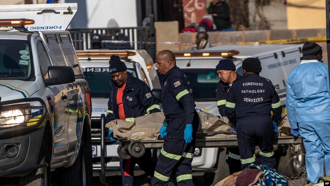 Membros do Serviço de Patologia Forense carregam uma das vítimas do tiroteio, Soweto, África do Sul