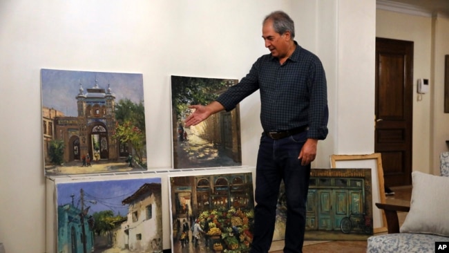 Painter Hassan Naderali shows some of his to artwork at his home in Tehran, Iran, June 20, 2022. The city's venerable buildings serve as his inspiration.