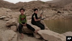 FILE - A 17 year-old boy holds his weapon at the High dam in Marib, Yemen, July 30, 2018. (AP Photo/Nariman El-Mofty, File)