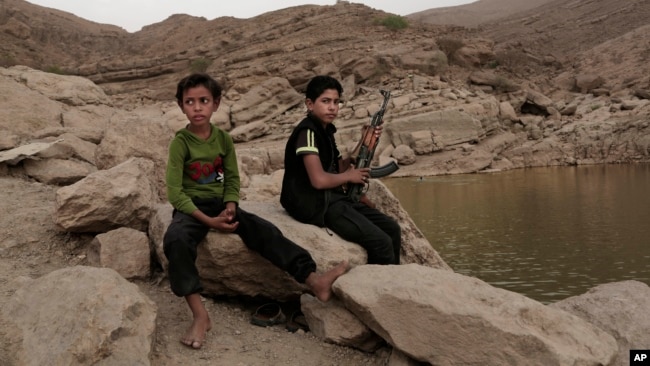 FILE - A 17 year-old boy holds his weapon at the High dam in Marib, Yemen, July 30, 2018. (AP Photo/Nariman El-Mofty, File)