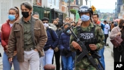 Un soldado pasa junto a los votantes que hacen fila en un colegio electoral durante la segunda vuelta de las elecciones presidenciales en Bogotá, Colombia, el domingo 19 de junio de 2022. (Foto AP/Jaime Saldarriaga)