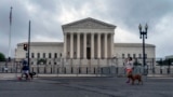 People walk dogs past anti-scaling fencing erected around the U.S. Supreme Court in Washington, June 23, 2022. (AP Photo/Gemunu Amarasinghe)