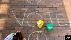 The oldest daughter of Lindsey Lurie fills in where her mother drew a heart on the sidewalk on July 5, 2022, near Highland Park, Ill., one day after a mass shooting. A shooter fired on the community's Independence Day parade from a rooftop.