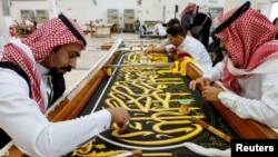 Para pekerja menyiapkan Kiswah, kain sutra yang menutupi Ka'bah, bangunan suci di tengah Masjidil Haram, menjelang haji tahunan, di sebuah pabrik di kota suci Mekah, Arab Saudi 6 Juli 2022. (REUTERS/ Mohammed Salem)