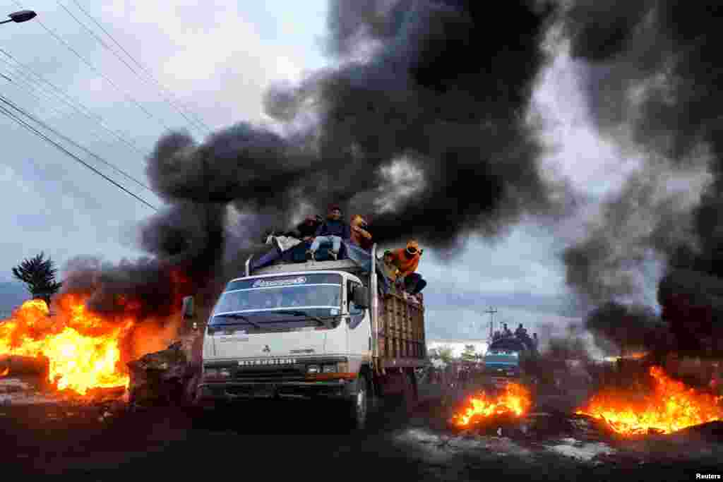 Indigenous demonstrators drive past burning road blockades while heading towards the capital Quito after a week of protests against the economic and social policies of President Guillermo Lasso, in Machachi, Ecuador, June 20, 2022. 