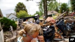 Melody Murter puts on a mask while helping to clean out a friend's home after it was damaged by severe flooding in Fromberg, Mont., June 17, 2022.