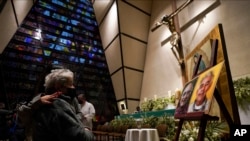 Una feligrés se lamenta frente a las imágenes de los sacerdotes jesuitas Javier Campos Morales y Joaquín César Mora Salazar durante una misa el martes 21 de junio de 2022, en la Ciudad de México. (AP Foto/Fernando Llano)