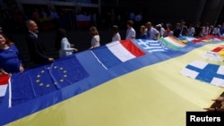 European lawmakers and Ukrainian representatives unfurl a Ukrainian flag outside EU Parliament, in Brussels, June 23, 2022.