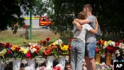 People lay flowers to pay last respects to victims of the Russian rocket attack at a shopping center in Kremenchuk, Ukraine, June 29, 2022. 