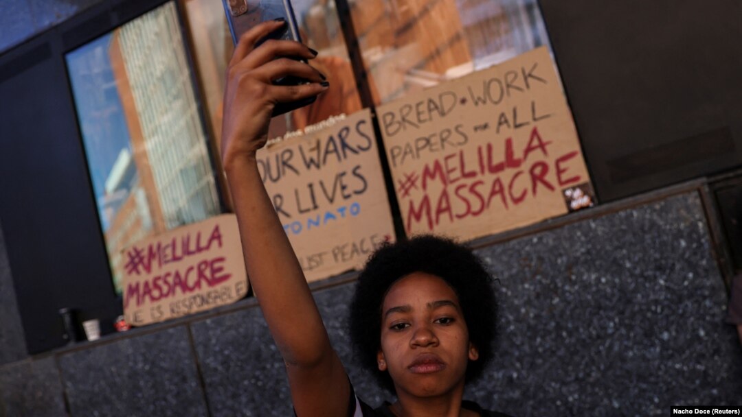 Uma mulher grava com seu celular pessoas protestando em Madrid na sequência da morte de pelo menos 23 imigrantes na sexta-feira durante uma tentativa de chegar ao enclave espanhol de Melilla. Espanha 26 de Junho de 2022