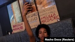 Uma mulher grava com seu celular pessoas protestando em Madrid na sequência da morte de pelo menos 23 imigrantes na sexta-feira durante uma tentativa de chegar ao enclave espanhol de Melilla. Espanha 26 de Junho de 2022