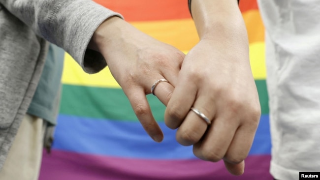 Plaintiffs hold hands with each other after a district court ruled on the legality of same-sex marriages outside Sapporo district court March 17, 2021, in this photo taken by Kyodo