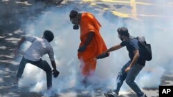 Protesters react after police fired tear gas to disperse them in Colombo, Sri Lanka, July 9, 2022. Sri Lankan protesters demanding that President Gotabaya Rajapaksa resign forced their way into his official residence on Saturday, a local television report