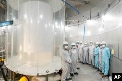 This photo provided by Sanford Underground Research Facility shows members of the LZ team in the LZ water tank after the outer detector installation in Lead, S.D. (Matthew Kapust/Sanford Underground Research Facility via AP)