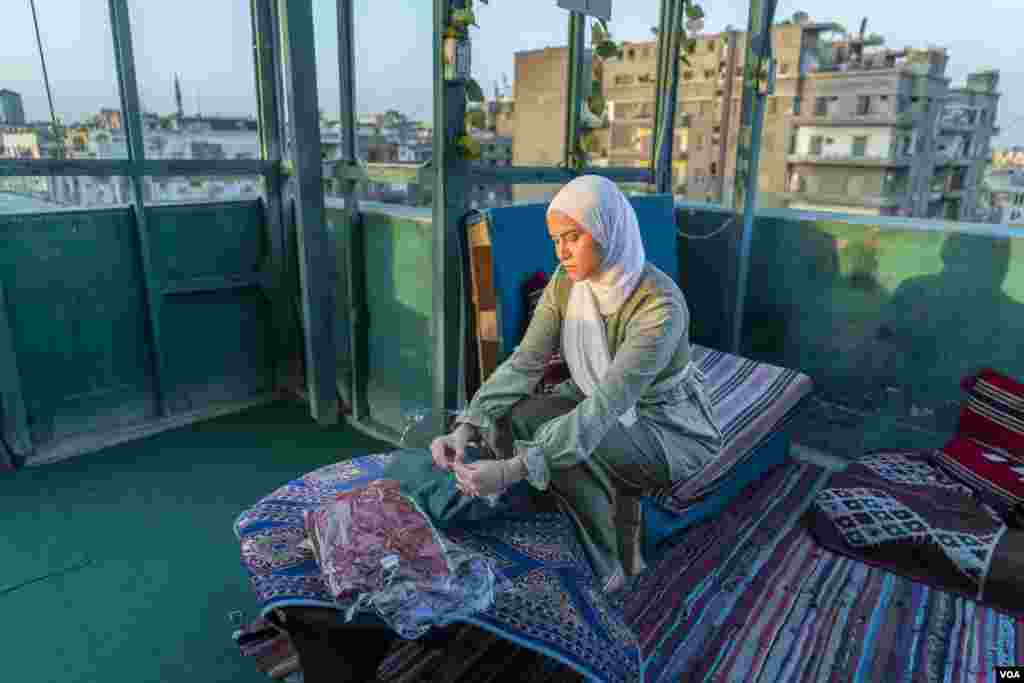 Radwa, an aspiring fashion designer, sorts items from her handmade, convertible clothing line for working- and middle-class women, in downtown Cairo, June 15, 2022. She says financial barriers stand between her and the growth of her business. 